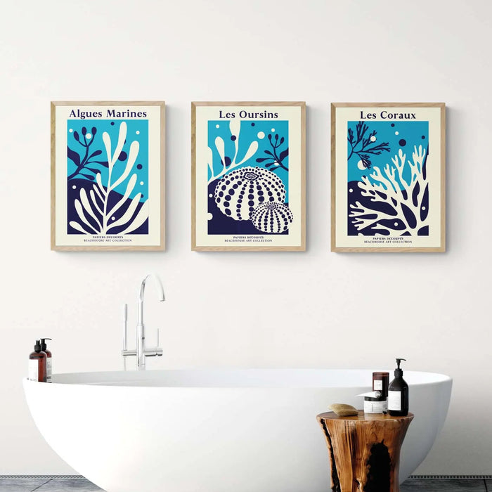 Set of three coral and seaweed art prints on the wall above a freestanding bath.