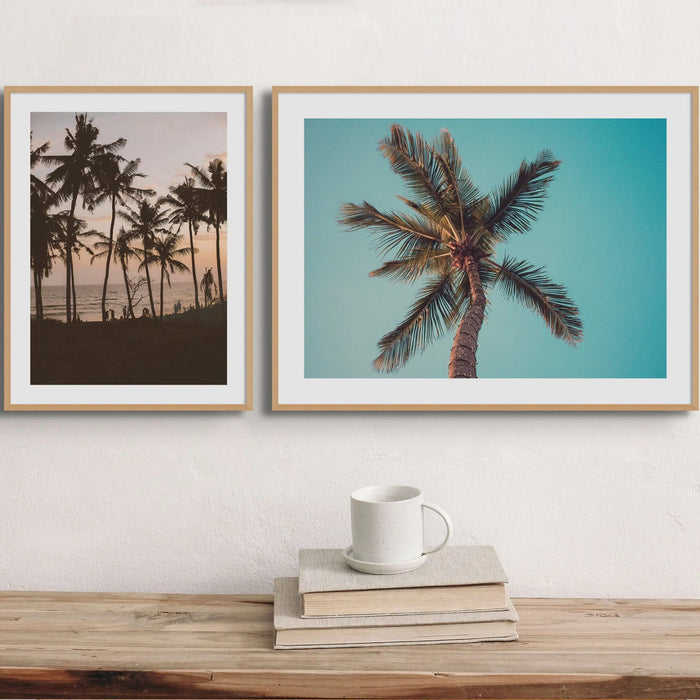 set of two retro-feel palm tree beach art photographs in oak frames above a timber side board - beach house art