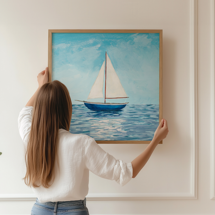 Woman hanging a framed painting of a sailboat on a wall