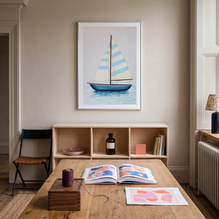 Room interior with a wooden table, bookshelf, and framed sailboat painting on the wall.