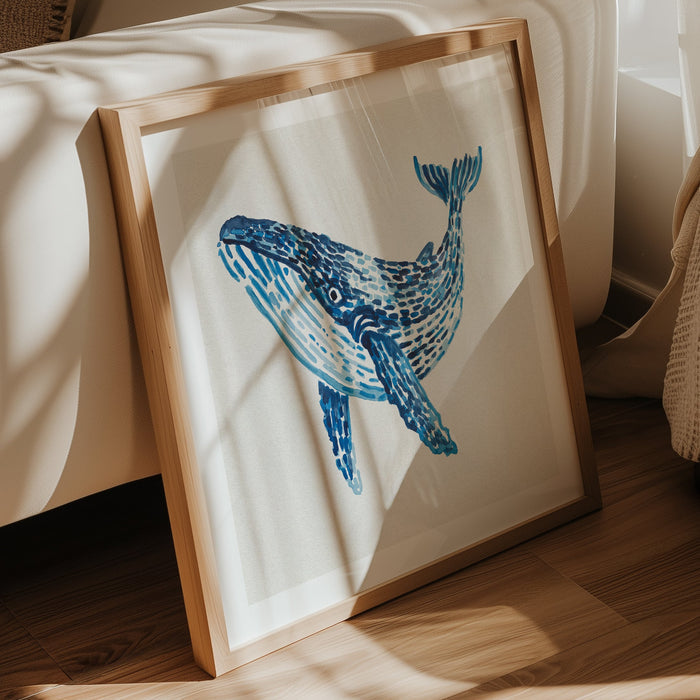Blue whale coastal art print painted with layered blue watercolour brushstrokes on a neutral background framed in wooden frame in living room