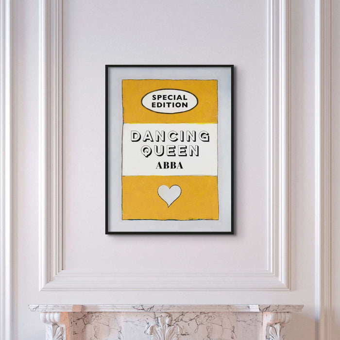 A print of a vintage book cover with the title 'Dancing Queen' by ABBA, predominantly yellow with black text, displayed on a white wall above a fireplace.