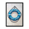 Framed artwork of a blue life buoy with 'Don't Give Up The Ship' text on a light wooden background.