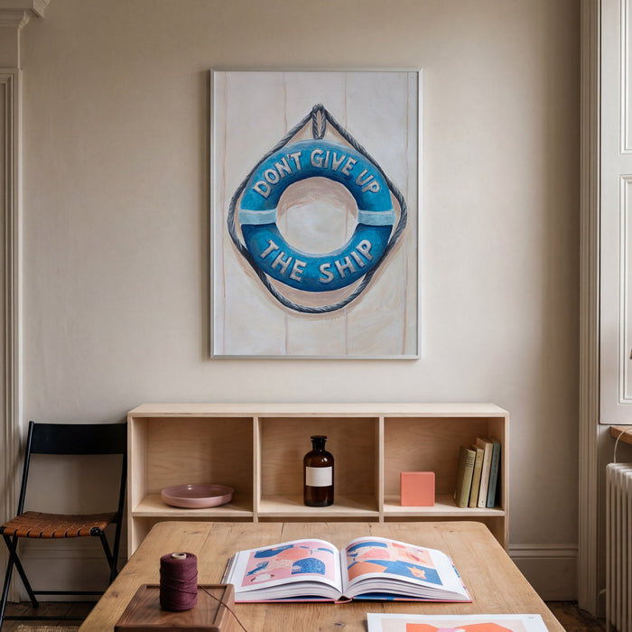 Nautical painting with a life buoy and a motivational quote in a room interior with a wooden table, a shelf, and wall art.