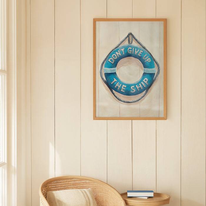 Framed artwork with motivational quote on a wall above a wicker chair in a bright room.