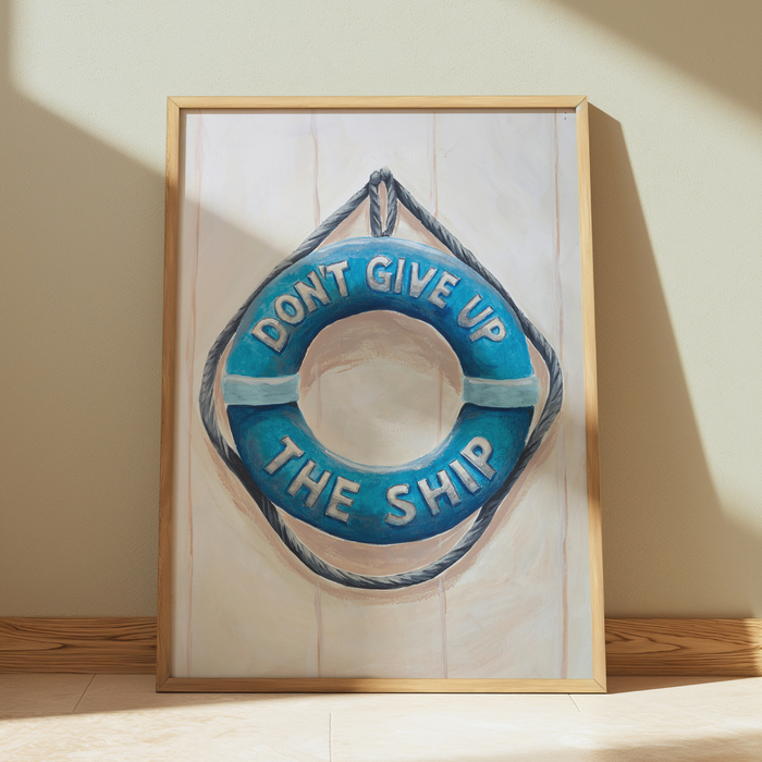 Framed artwork of a blue life buoy with 'Don't Give Up The Ship' text on a wooden shelf.