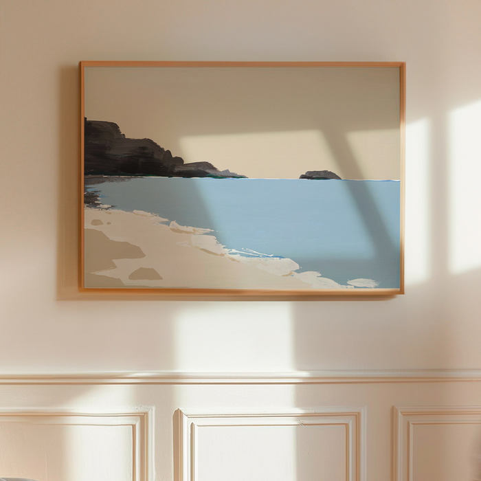 Framed artwork of a beach scene on a wall with wainscoting.