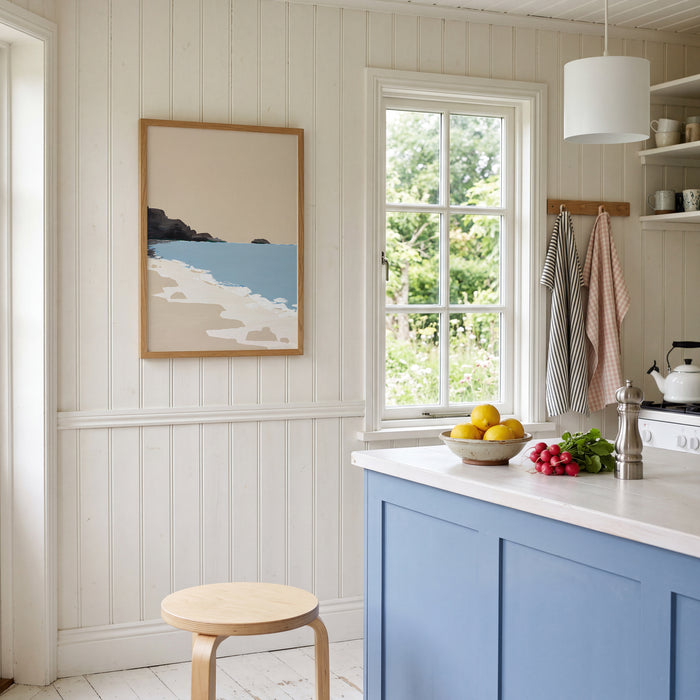 Kitchen interior with a beach-themed painting on the wall, window, and countertop items.
