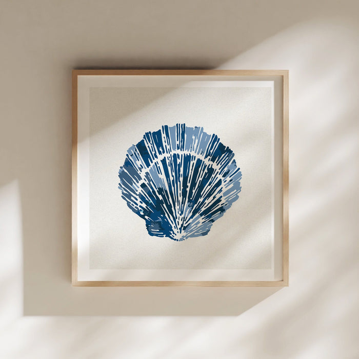 Framed indigo scallop shell wall art in natural wood frame, styled on a light neutral wall with soft shadows.