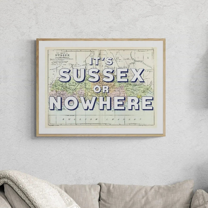 A vintage Sussex map print with the text 'It's Sussex or Nowhere' overlayed on a map background, in a natural wood finish frame.