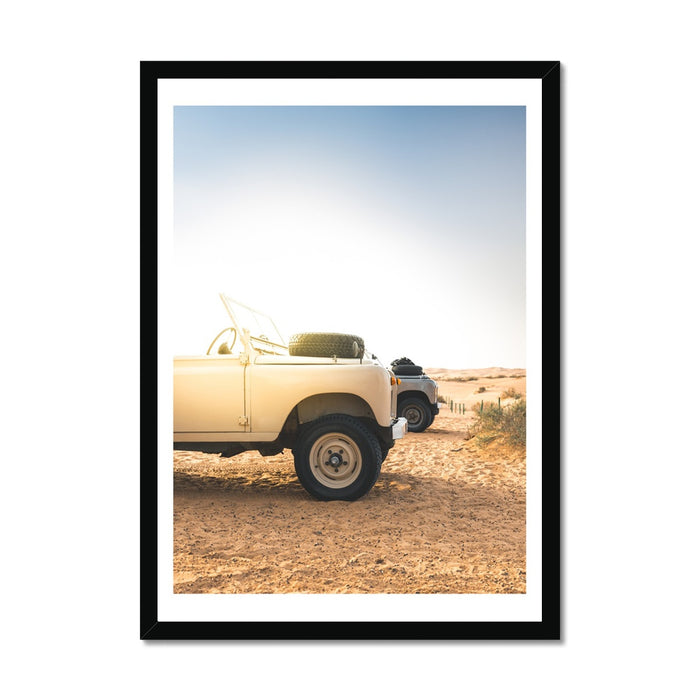 A framed art print of a Land Rover Defender parked on a beach at dawn.