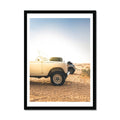 A framed art print of a Land Rover Defender parked on a beach at dawn.