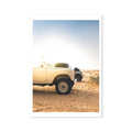 A photography print of a beige Land Rover Defender parked on a beach at dawn.