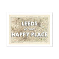 A framed map print of Leeds featuring a map with the text 'Leeds is our HAPPY PLACE' overlayed on it.