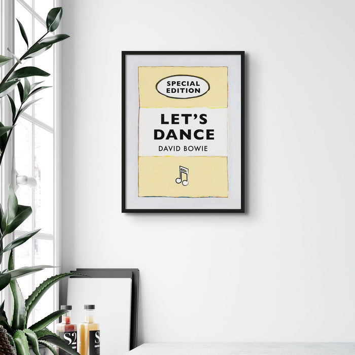 A print of a vintage book cover with the title 'Let's Dance' by David Bowie, predominantly yellow and black in color, with the text arranged in a simple, bold typography style.
