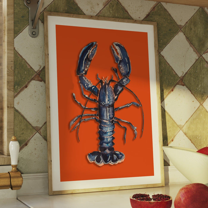 Framed artwork of a blue lobster on an orange background, displayed against a patterned wall.