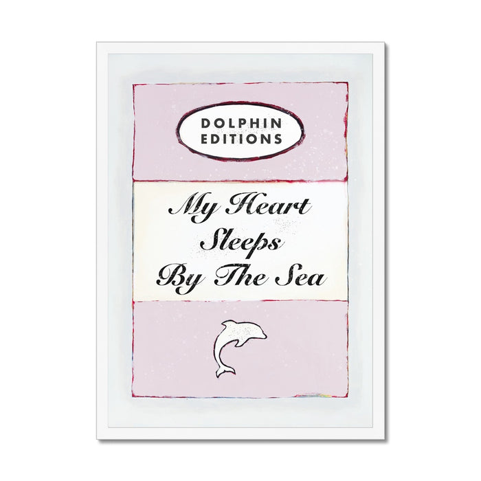 Framed art piece featuring a vintage book cover print with the title 'My Heart Sleeps By The Sea' on a pink background.