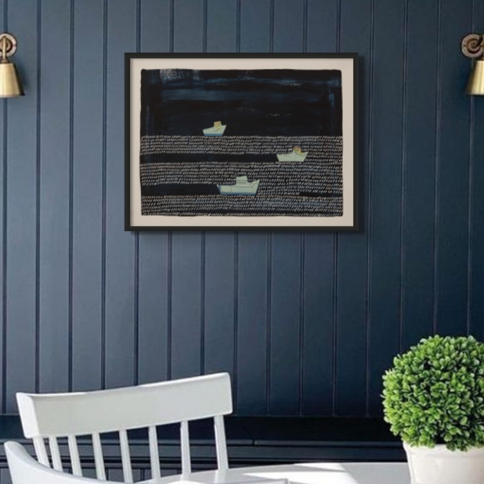 A framed art print featuring a modern seascape with boats on the water, framed in dining room on blue wall.
