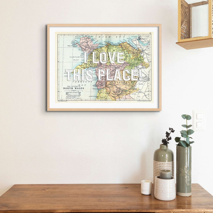 A framed custom map print of North Wales with a white vintage font covering part of the map details, where text can be personalized.