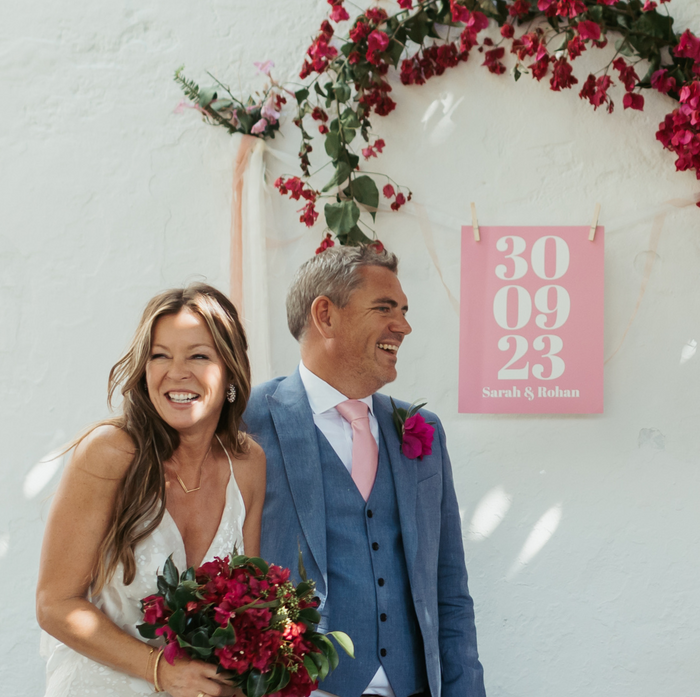 couple getitng married in front of a custom wedding art print with the date of their wedding and their names printed