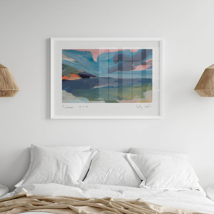 A framed abstract landscape painting of Porthmeor beach in Cornwall in coastal themed bedroom. Featuring textured brushstrokes of blue, green, pink, and orange, presented in a black frame with a white mat on a light grey background.