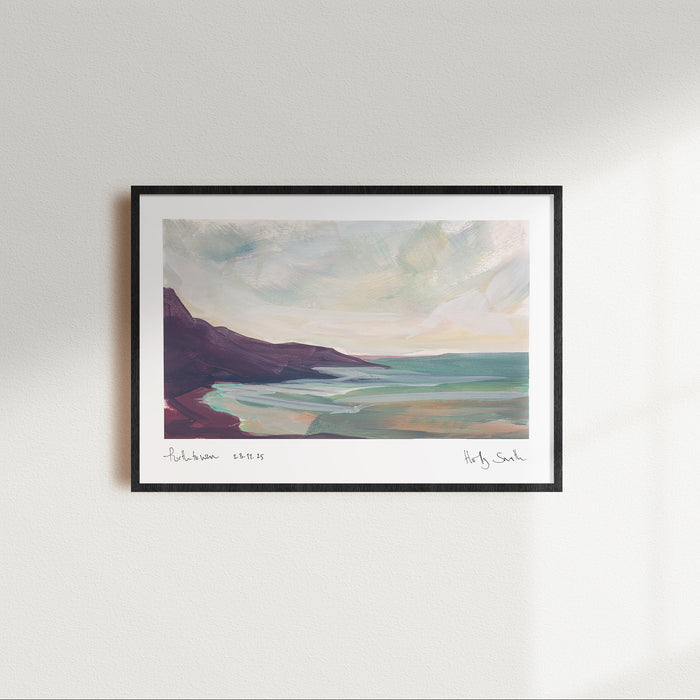 A framed landscape art print of Porthtowan in Cornwall featuring an impressionistic painting of a coastal scene with dark cliffs, turquoise water, and a cloudy sky, shown against a plain white background.
