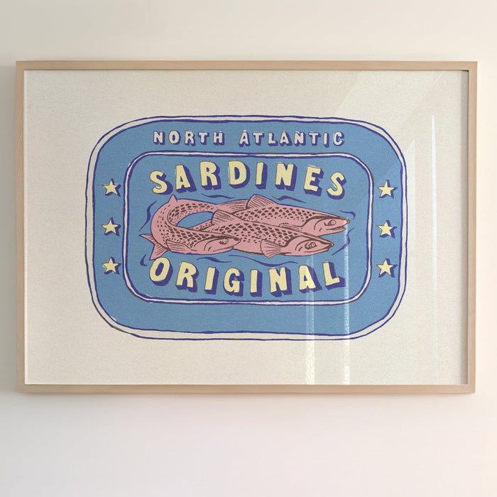 Framed artwork of a label depicting 'North Atlantic Sardines Original' with a stylized fish illustration in red and blue.