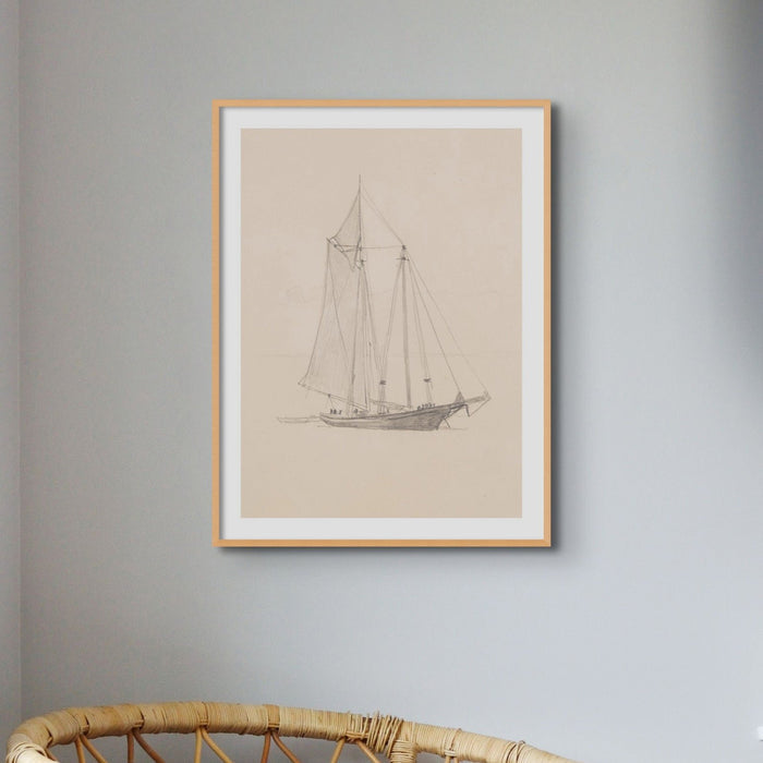 Framed art print of a vintage pencil drawing of a schooner sailing boat with a dinghy on the wall above a chair.
