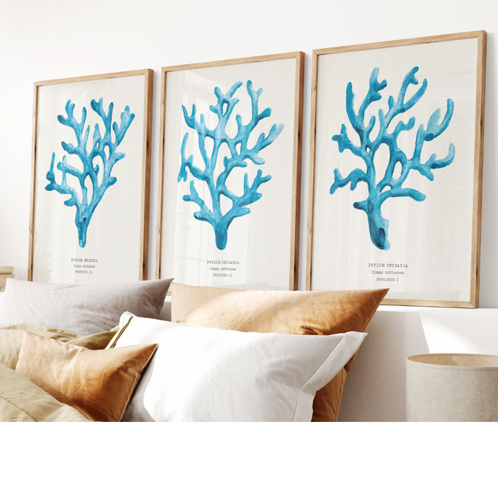 Set of three coral art prints - coral paintings as a set framed in natural frame above a bed.