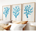 Set of three coral art prints - coral paintings as a set framed in natural frame above a bed.