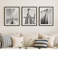 Set of three sailing prints in living room. Three framed black and white sailing photography artworks above a beige sofa with striped cushions.