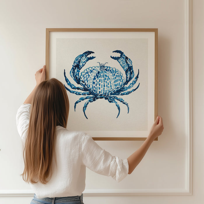 A framed watercolour painting of a crab in indigo blue being hung on wall.
