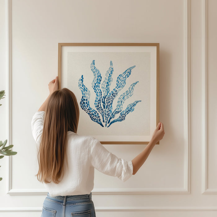 Watercolour seaweed print in blue, framed and being hung on wall