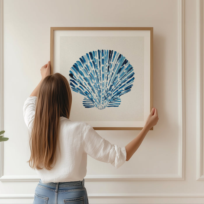Scallop shell art print with layered blue watercolour brushstrokes on a neutral background, contemporary coastal wall art. Framed in natural wood frame.