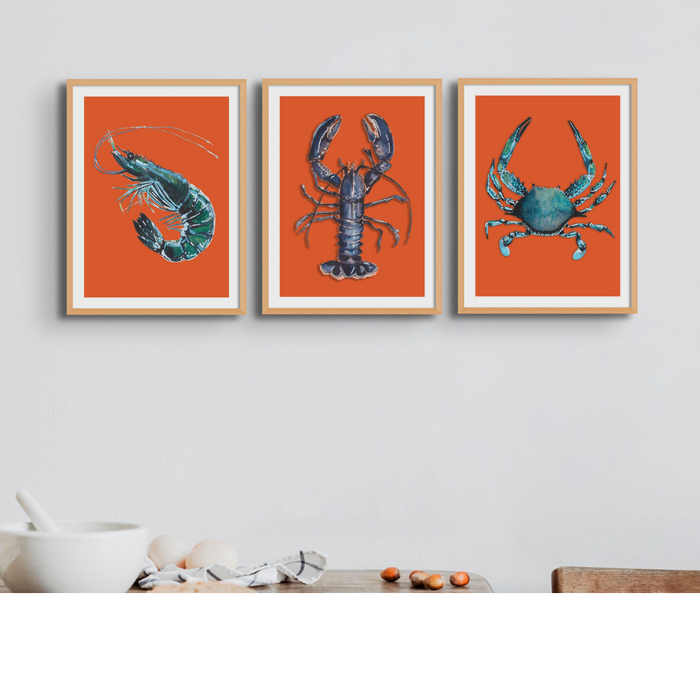 A set of three framed prints featuring colorful illustrations of shellfish on a red background, displayed on a wall.
