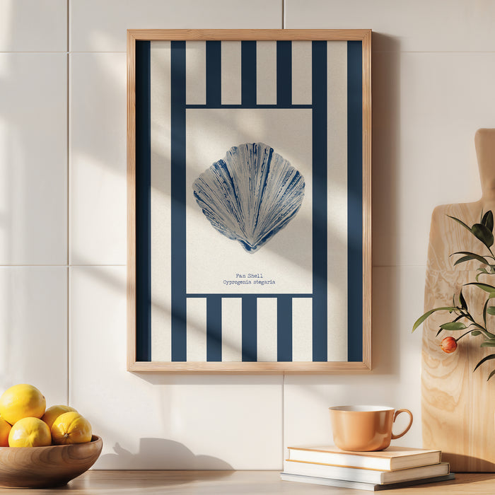 Framed artwork of a blue shell on a white background with blue stripes, displayed on a wall above a table with books and a cup.