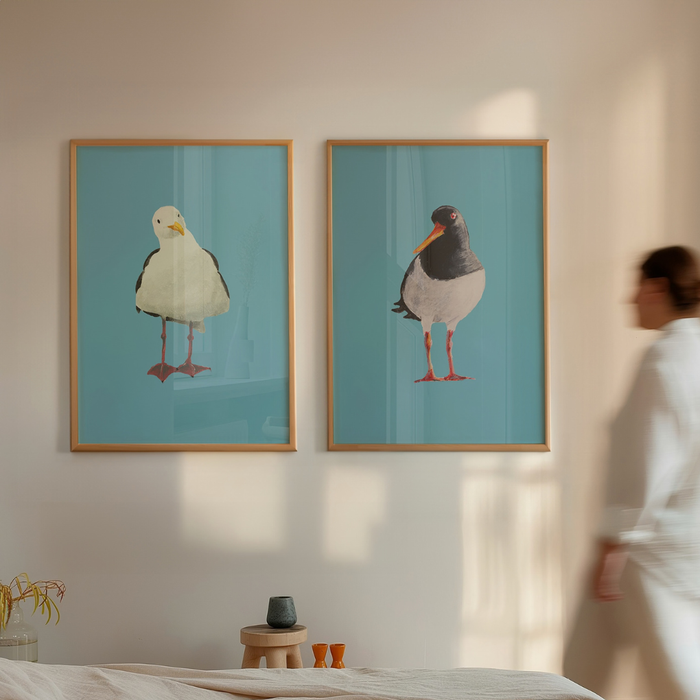 Set of two framed bird prints on a wall i bedroom with a person partially visible.