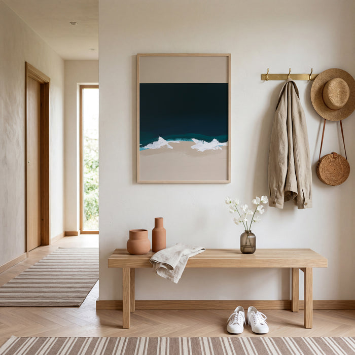 Modern entryway with wooden bench, framed coastal artwork, and hanging items.