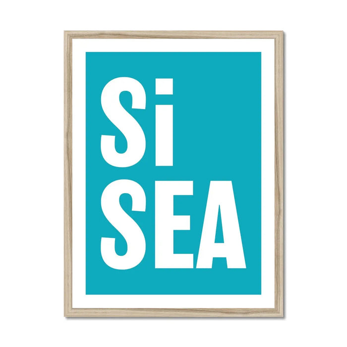 A framed typography art print with the words 'Si Sea' in large white letters on a teal background, framed in a simple natural frame.