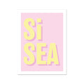 A framed typography art print with the words 'Si Sea' printed in bold yellow letters on a pink background.