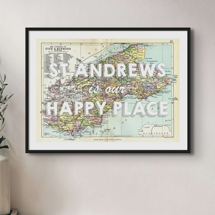 Framed vintage map print of St Andrews featuring text 'St Andrews is my Happy Place' on a colorful map background, encased in a black frame.