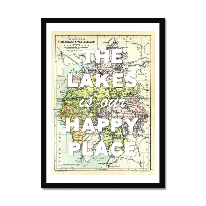 A framed map print of the Lake District with black frame. A vintage map with the text 'The Lakes is our Happy Place' overlaid on it.