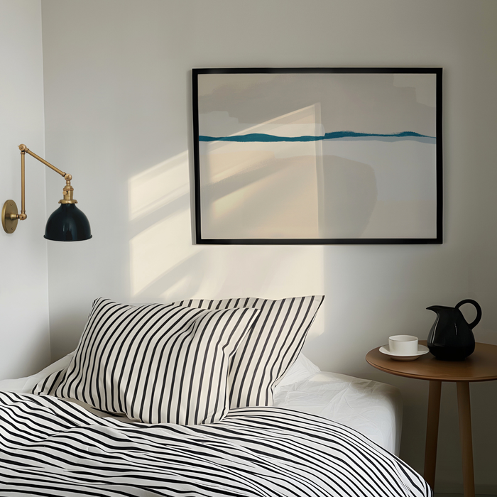 Bedroom with striped bedding, a lamp, and a framed abstract painting on the wall.