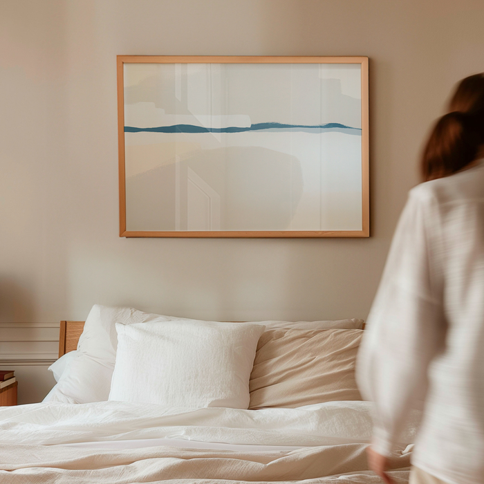 Woman standing by a bed with a abstract painting on the wall