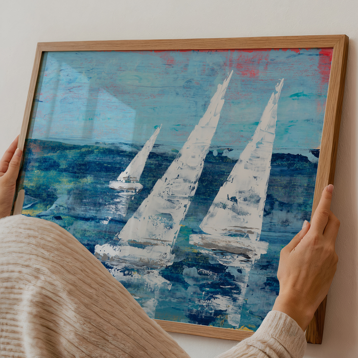 Person holding a framed painting of sailboats on a blue ocean