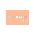 An art print with the text 'VITAMIN Sea' on a peach-colored background, presented in a simple white frame.