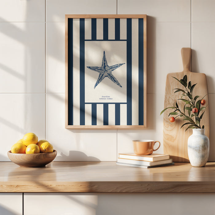 Framed shell artwork with a starfish design on a wall above a wooden surface with a bowl of lemons, books, and a vase.