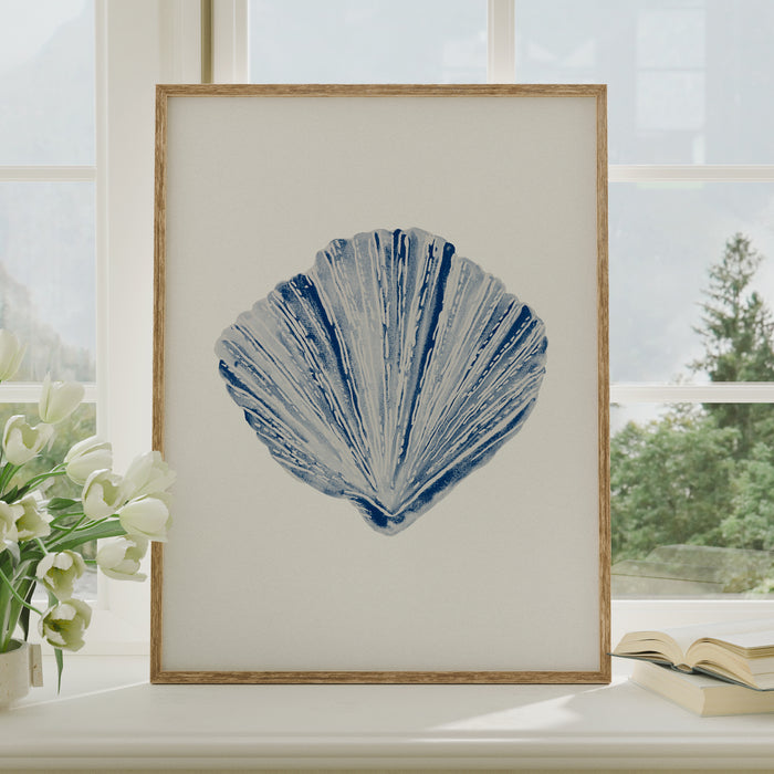 A framed shell art print on shel by window.