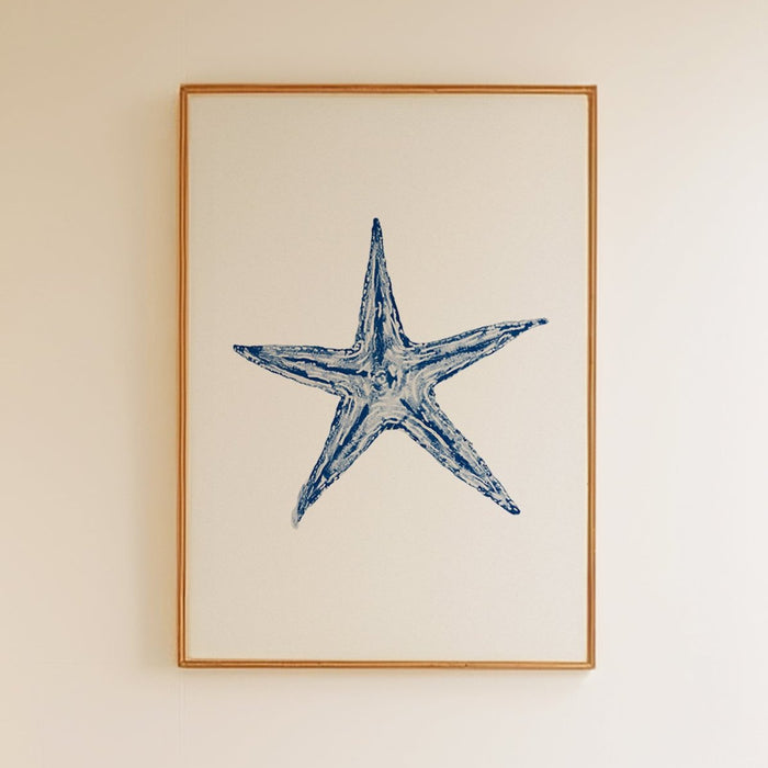A framed painting of a starfish on white wall with wooden frame.
