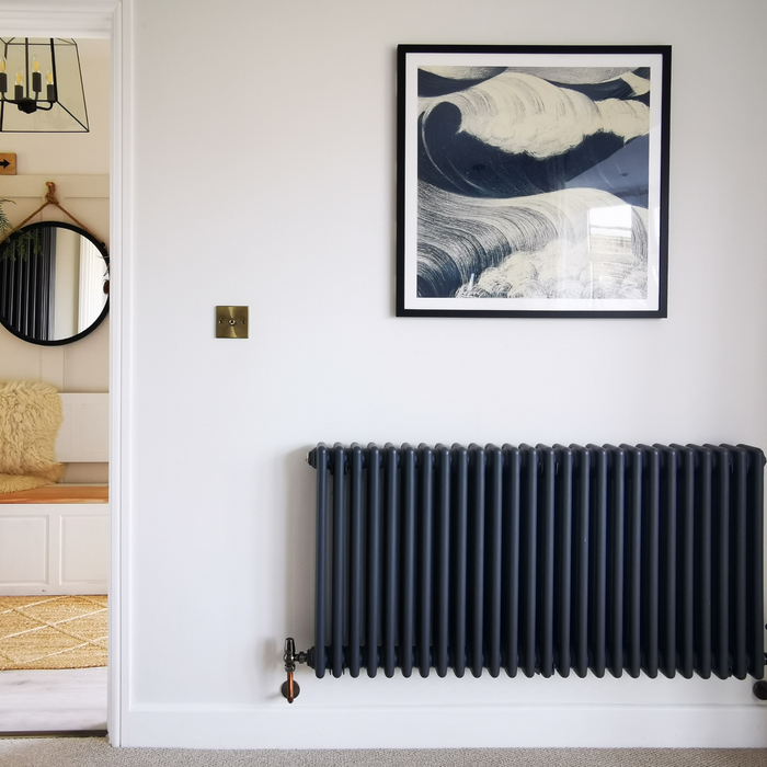 Wave art print - blue sea painting with black frame on white painted wall.